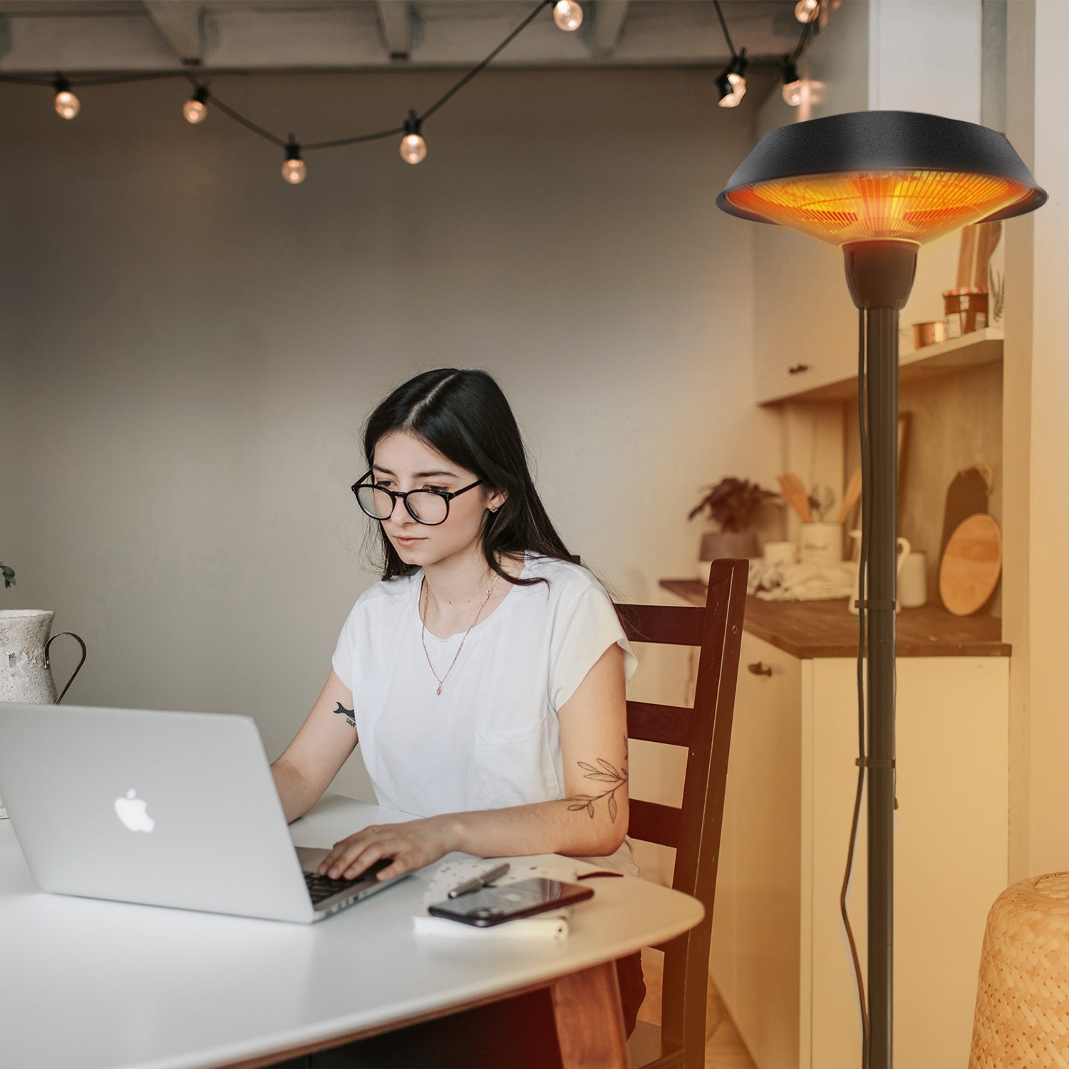 Girl working on laptop sitting beside an electric heater 