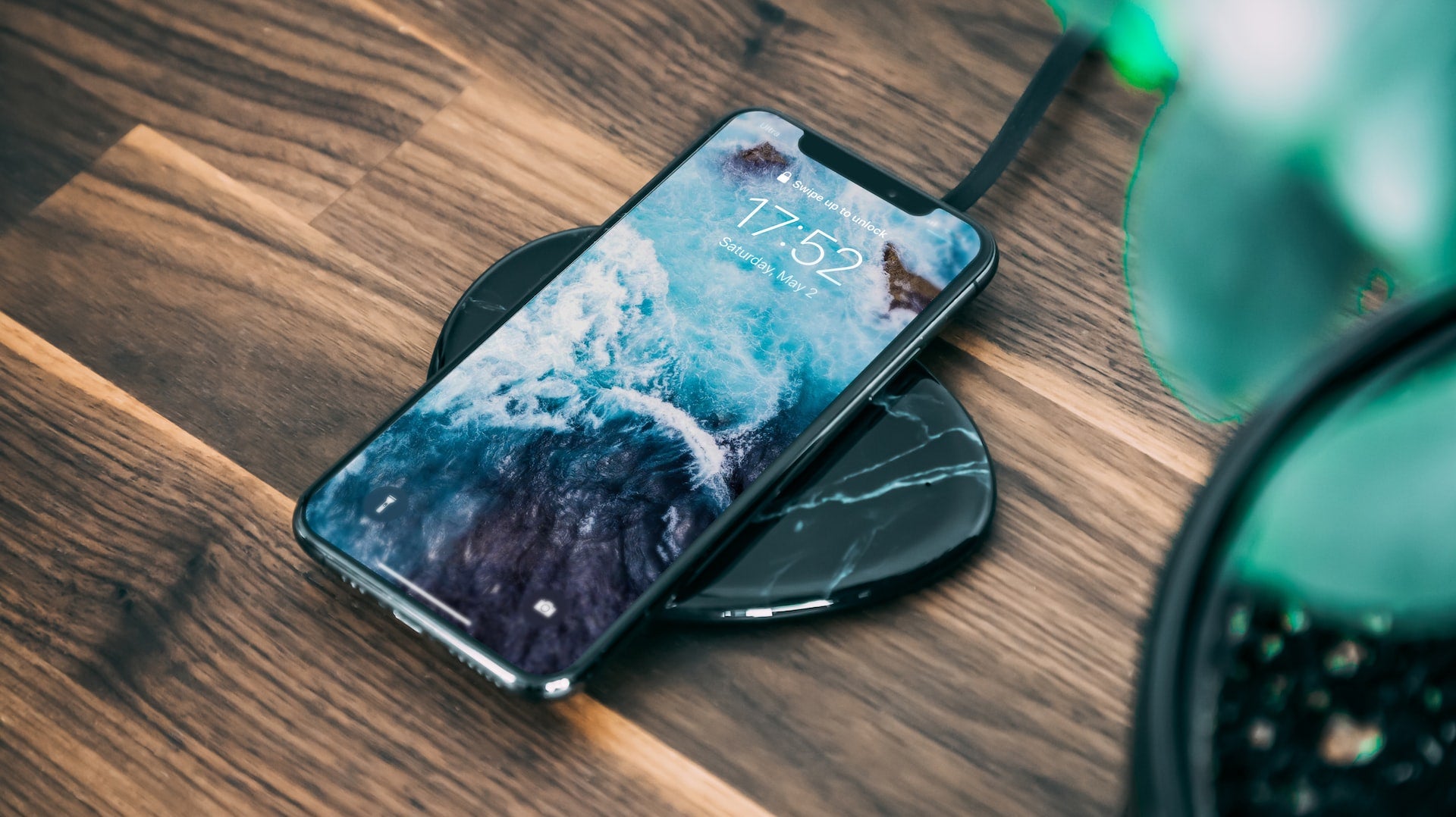 black iPhone charging via a wireless charger on a tabletop