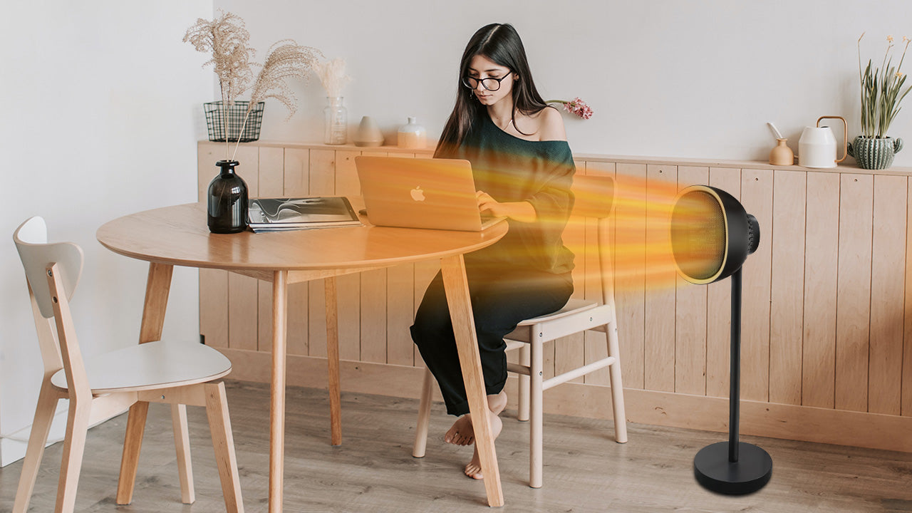 Girl working on laptop sitting beside an oscillating heater 