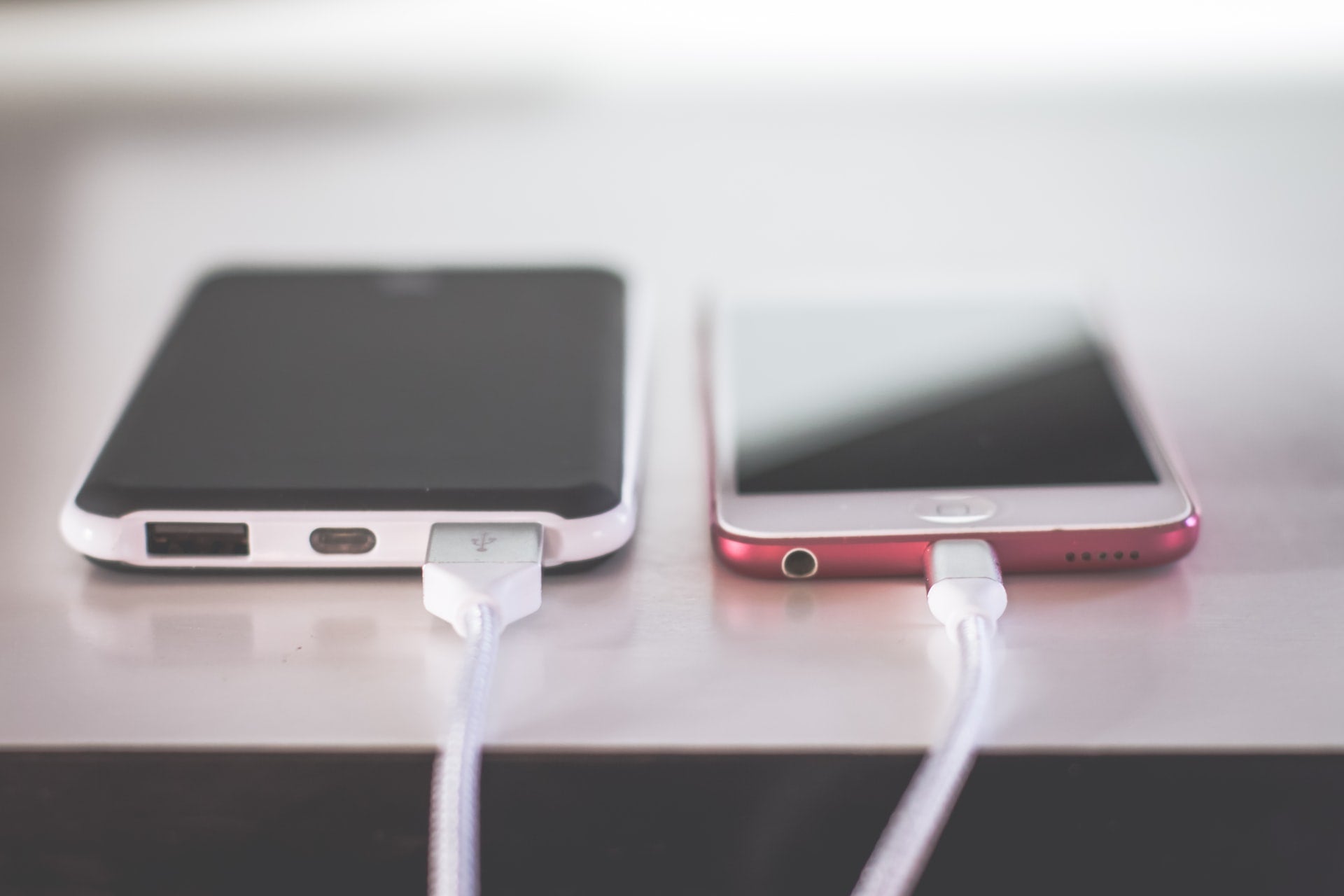 two cell phones charging via wired charger on a table